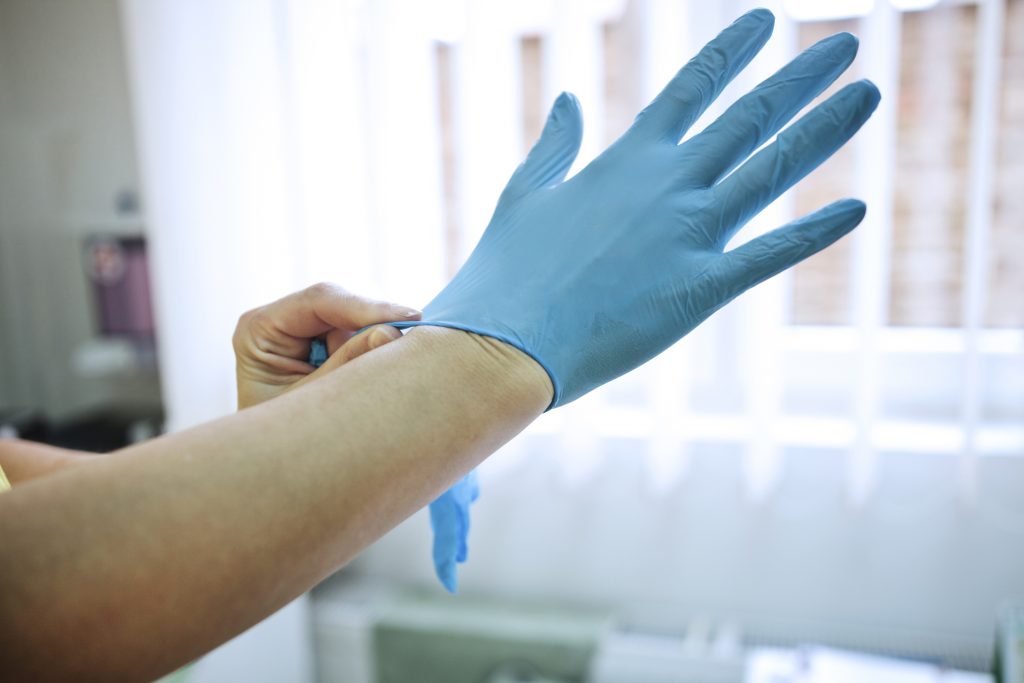 Doctor putting on medical gloves Off the Cusp