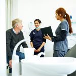 A dentist talks with two staff members in a dental office.