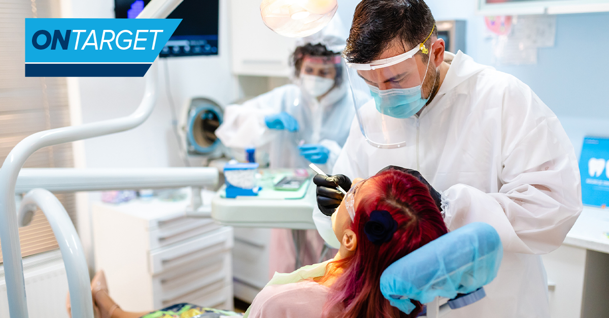 Dentist with patient in operatory with dental assistant in background