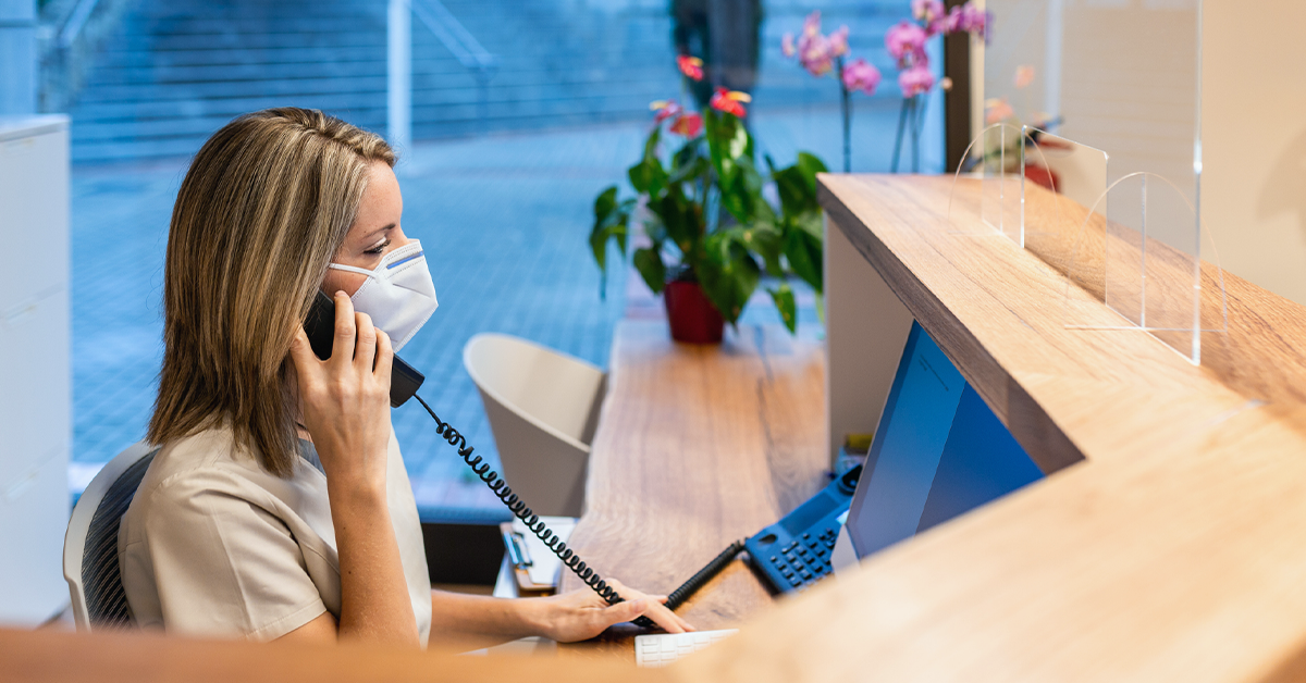 Dental practice manager taking a call at the reception area.