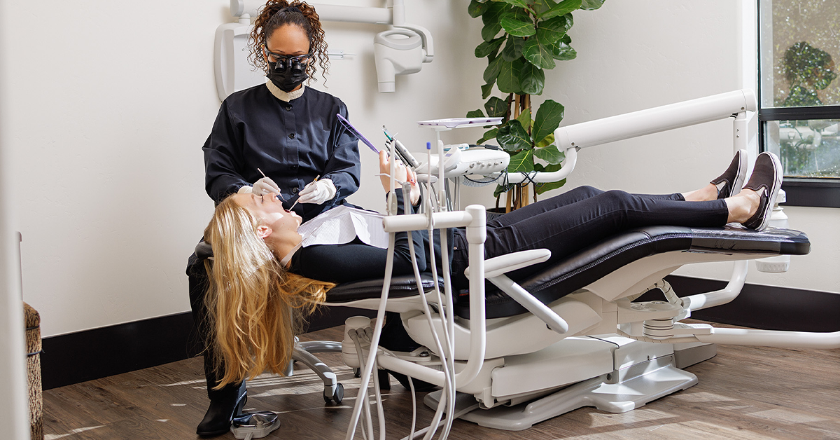 Photo of a dental hygienist with a patient in a dental chair.