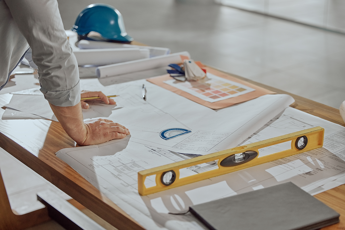 Dental office design plans and architectural blueprints on a table with construction tools, illustrating the planning and renovation process for a modern dental practice.